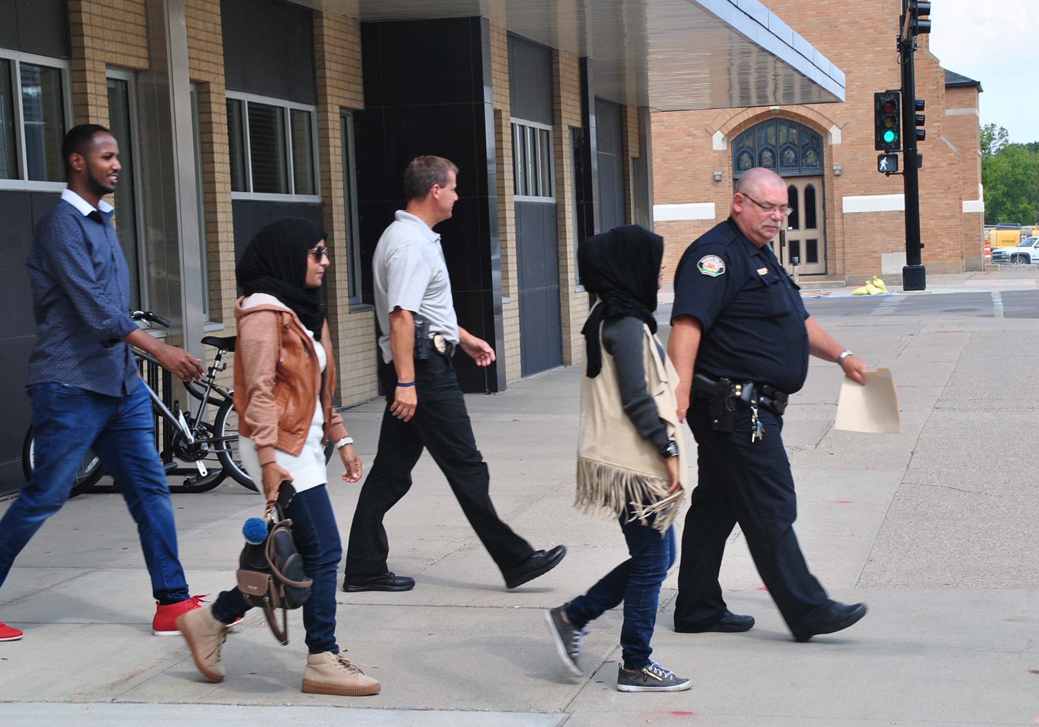 The Hassan sisters accompany police officers to a scheduled meeting with their attacker - photo by C.S. Hagen