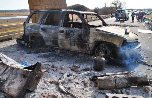 Burned out vehicle sitting before Backwater Bridge - photo by C.S. Hagen