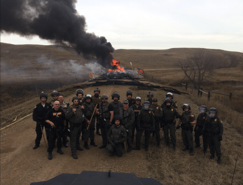 Police gather for a photo opp before a roadblock setup by activists reports differ on who set the debris on fire - photo provided by online sources