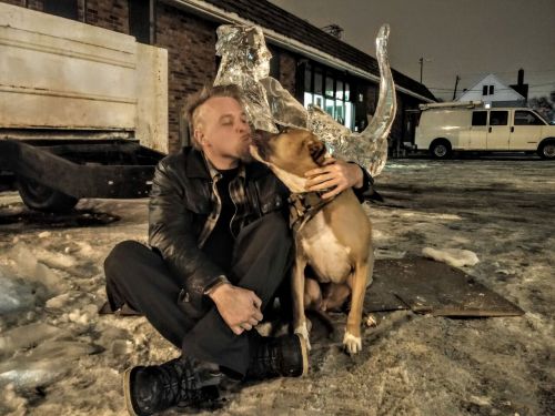 Chainsaw Dave and his Pitbull, Artie, sitting before one of his sculptures - Photograph by Sabrina Hornung