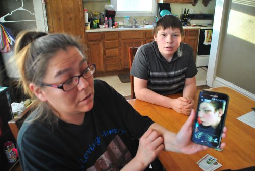 Jackie Charbonneau and her son, Christopher L. Thumb, who is also pictured with two black eyes, and a split lip on cell phone - photograph by C.S. Hagen