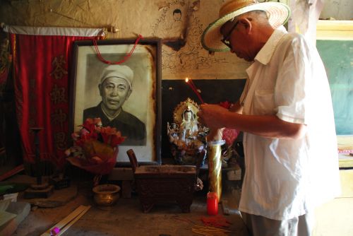 Lei Ying, eldest son of the Boluo Fox, lights incense before a picture of his father in the old clinic - photograph by C.S. Hagen