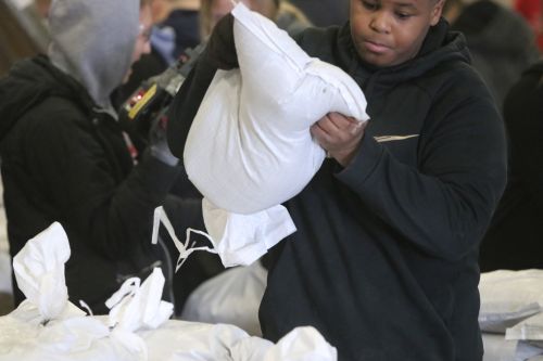 Student lifting 30-pound sandbags to help fight Fargo's Spring Flood 2019 - photograph by C.S. Hagen