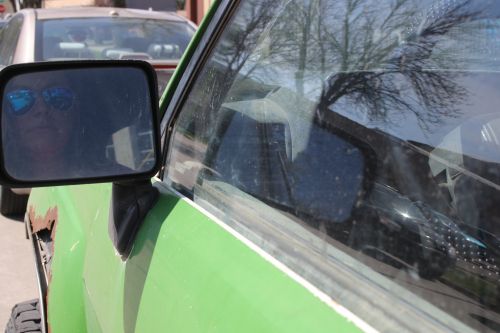 Sarah Gulenchy in her car the Toyota Zombie looking at the sideview mirror - photograph by C.S. Hagen