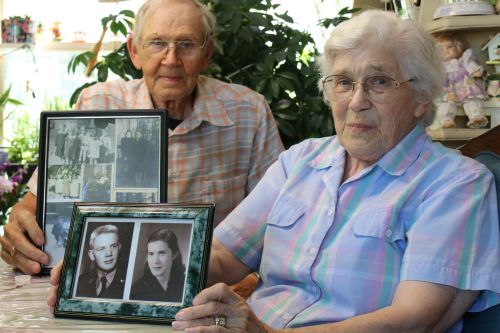 Gerda and Arnold Jordheim holding up framed pictures of their younger selves at their home in Walcott - photograph by C.S. Hagen