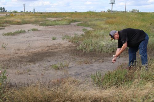 Daryl Peterson a retired Bottineau County farmer checking for salt levels at a spill site - photograph by C.S. Hagen