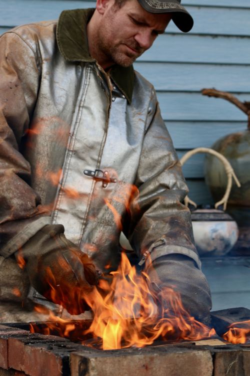 Award winning potter, Brad Bachmeier, pit firing his pottery at his studio - photograph by C.S. Hagen.