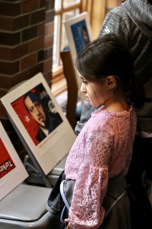 A young girl looks on a protest posters containing pictures of the Turkish president - photograph by C.S. Hagen