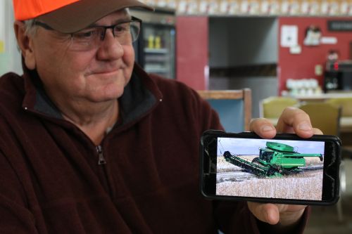 Bob Bowerman, a Kidder County farmer, holds up a picture of his combine stuck in the mud - photograph by C.S. Hagen