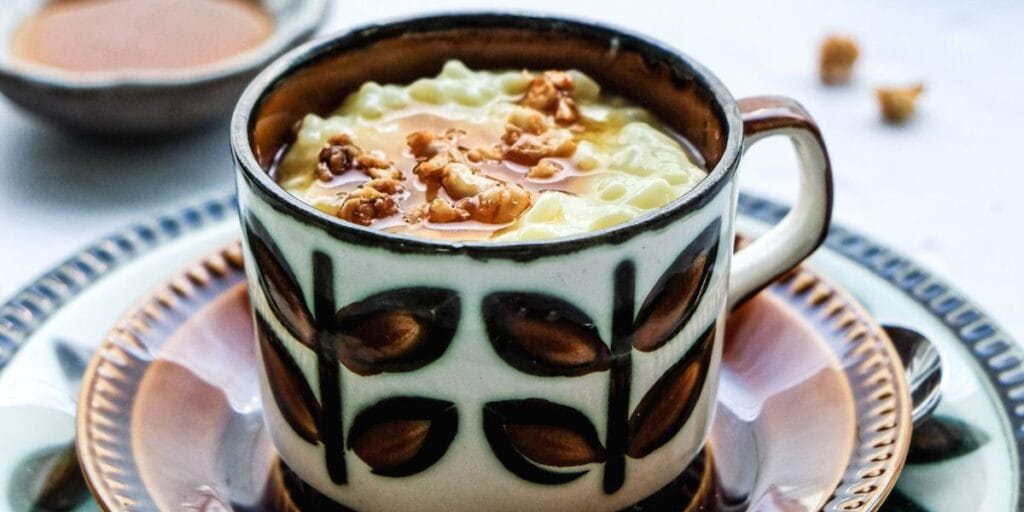 Rømmegrøt, a creamy Norwegian porridge topped with nuts and syrup, served in a decorative mug