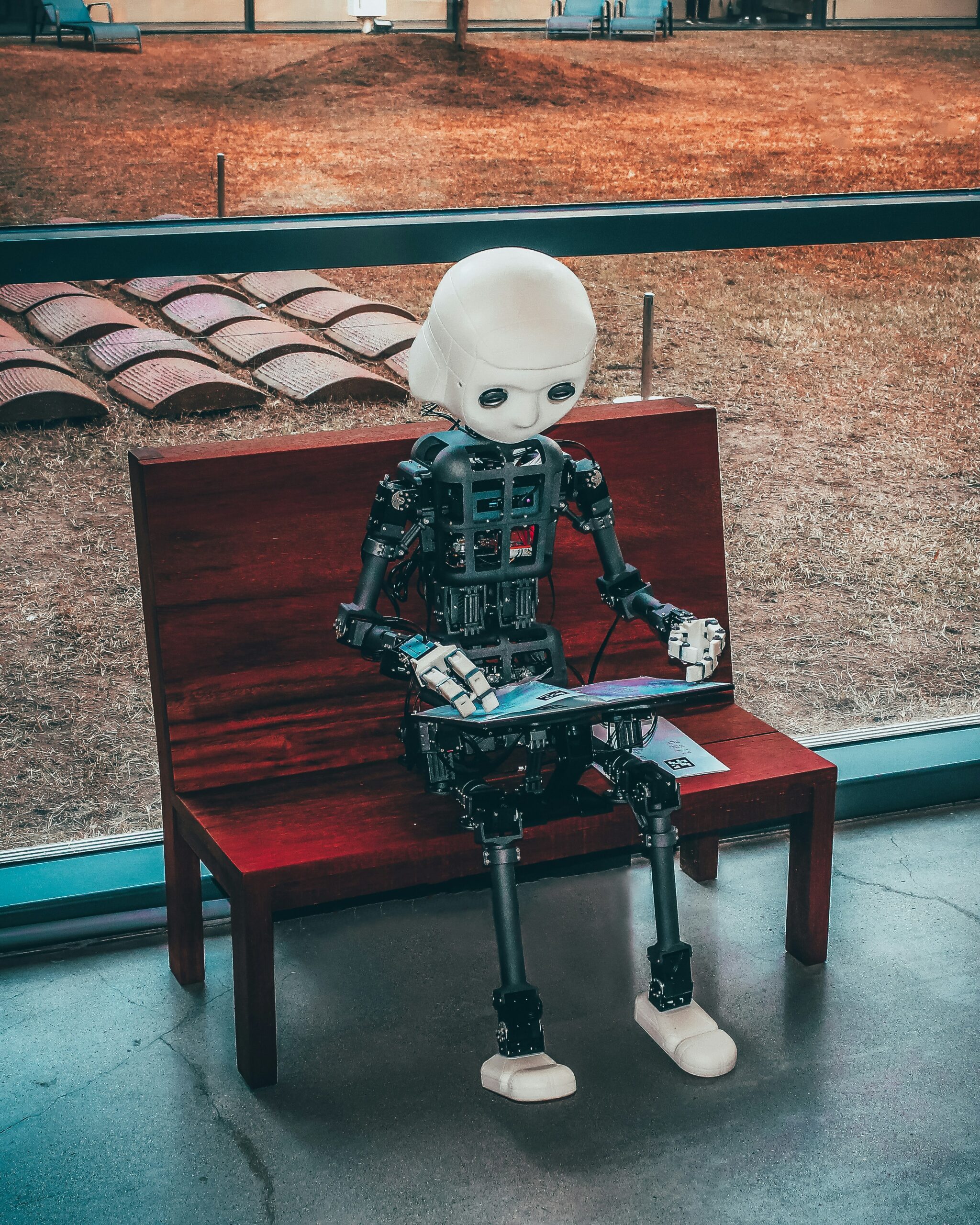 A small humanoid robot sitting on a red bench