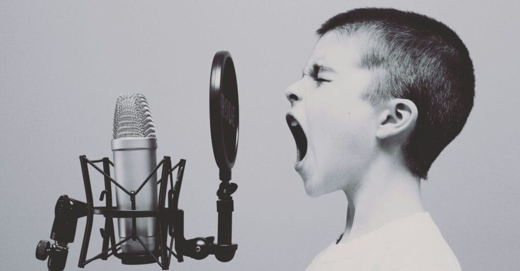 Boy shouting into professional studio microphone with pop filter